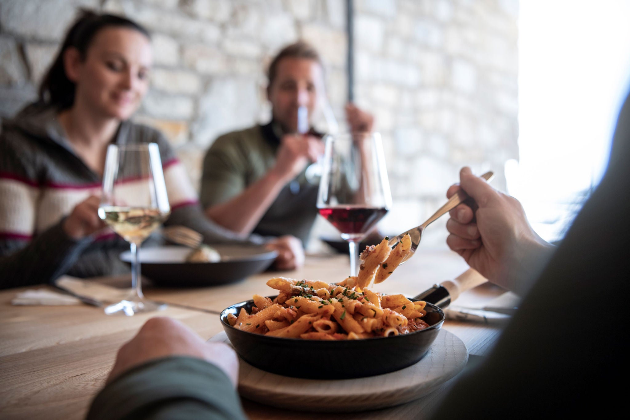 Eine Gruppe von Personen essen diverse Gerichte auf einer Hütte