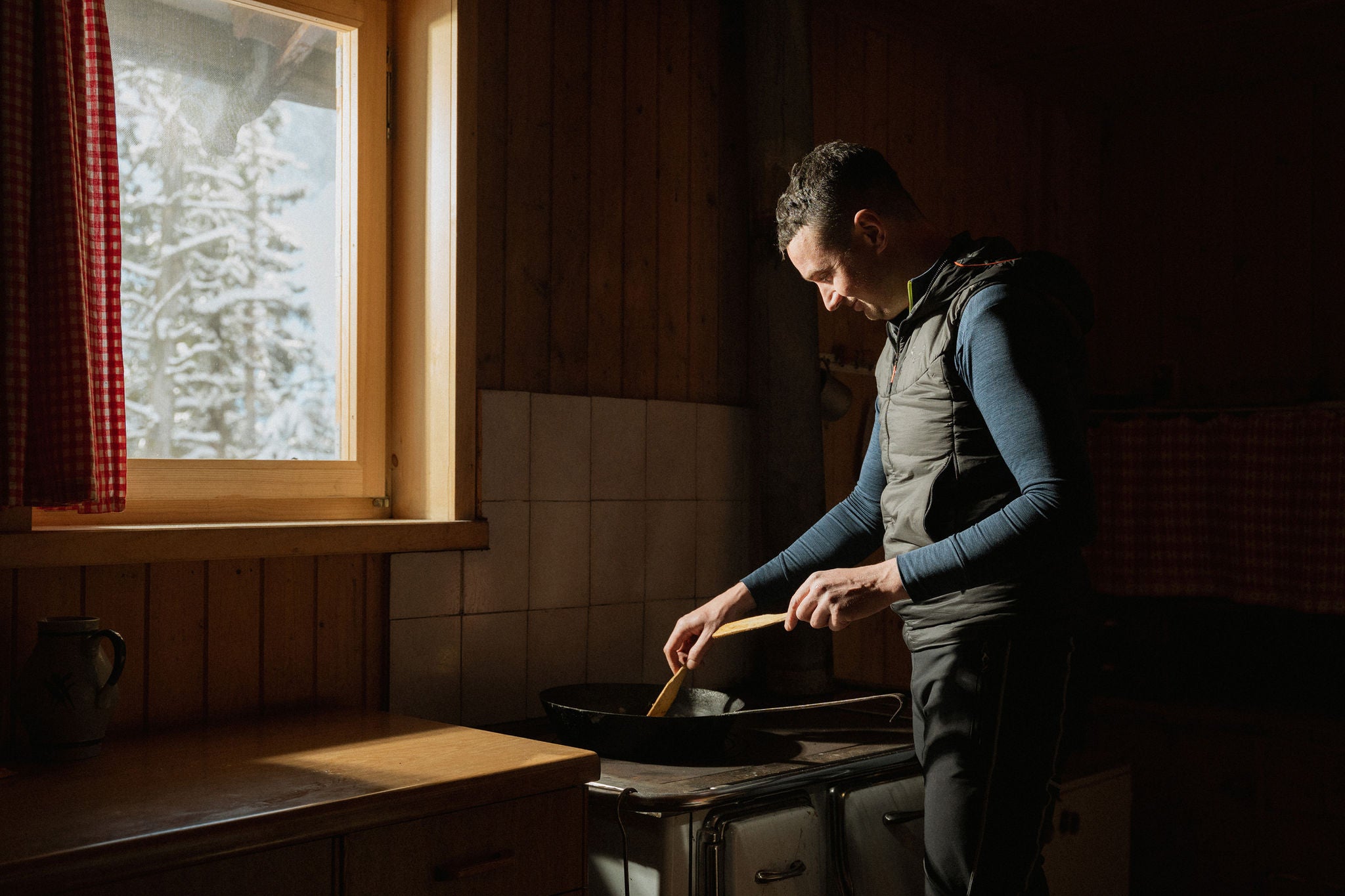 Ein Mann beim Kochen in rustikaler Hütte im Villnösstal im Winter