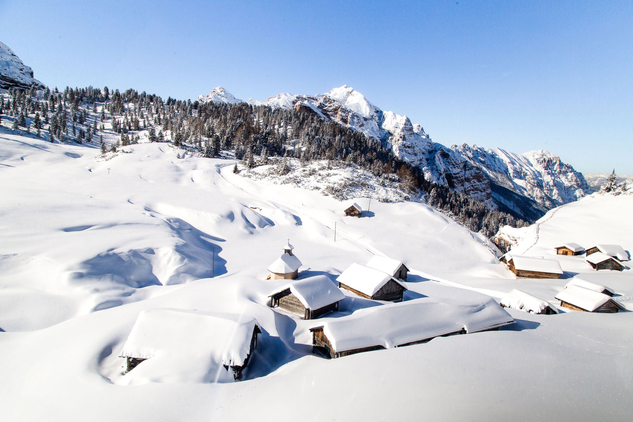 Schneebedeckte Almhütten unter strahlend blauem Winterhimmel