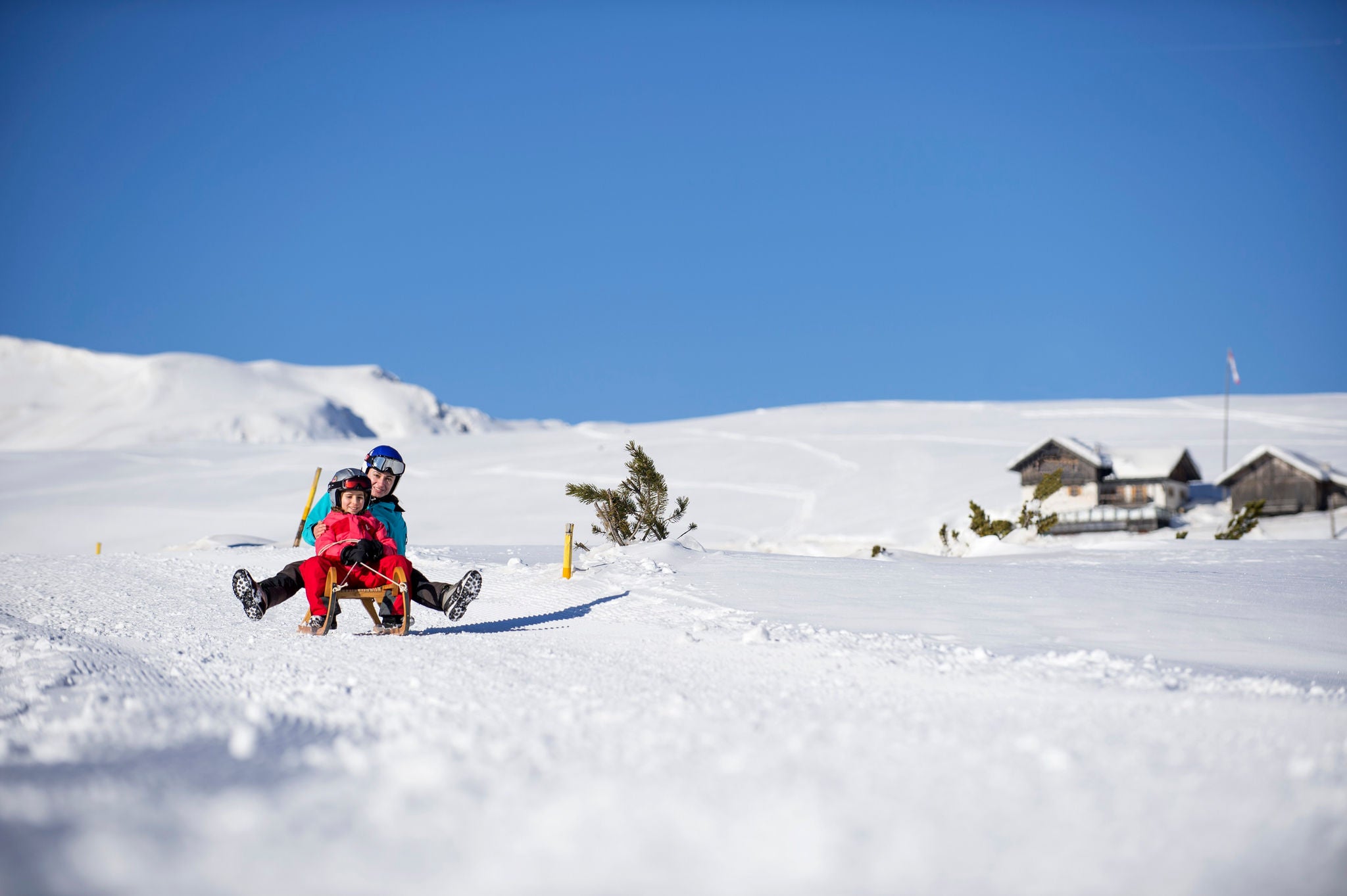 Eine Frau und ein Kind rodeln auf einem Schlitten auf der Villanderer Alm.