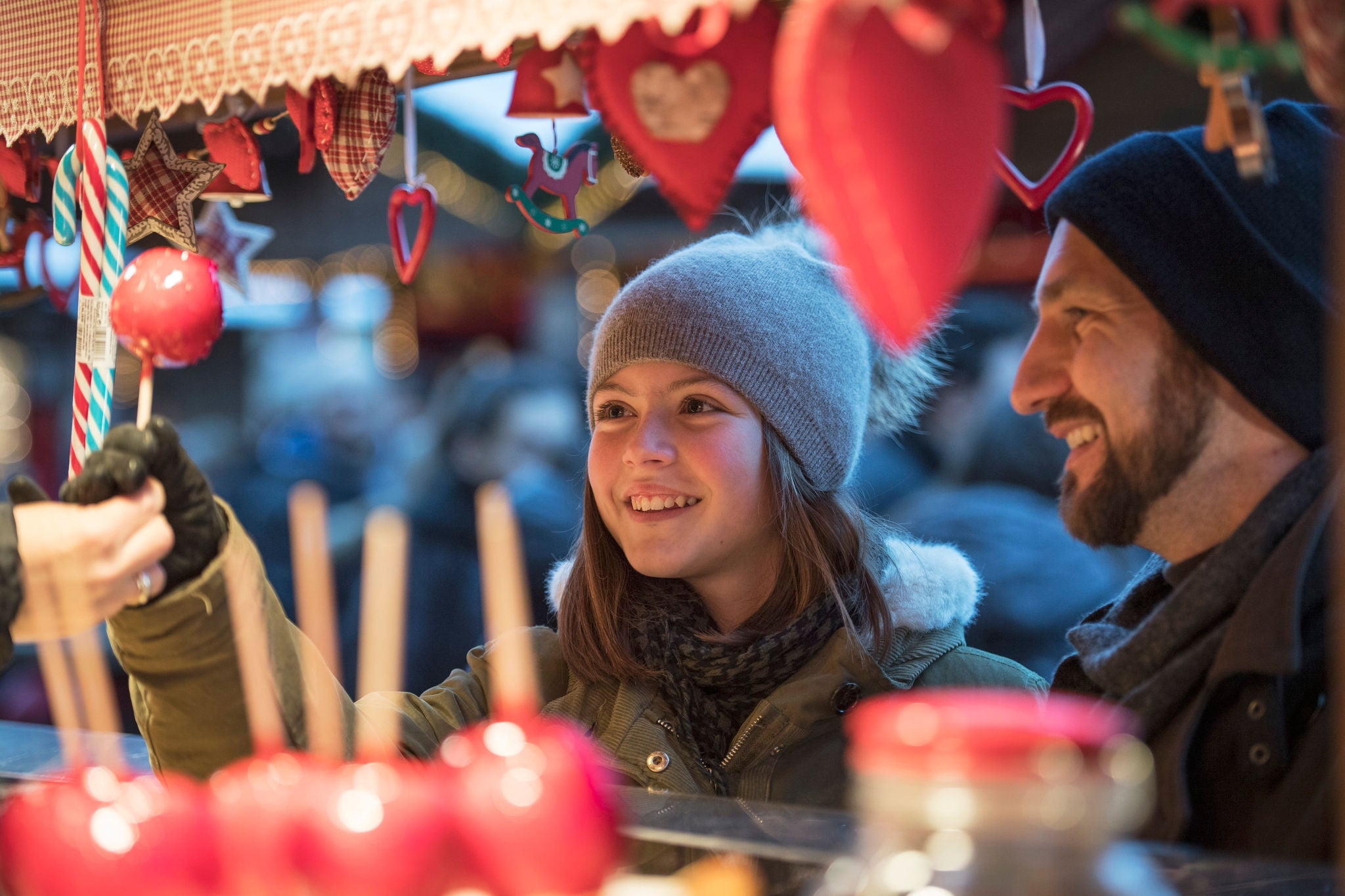 Ein Mädchen und ein Mann schauen auf einen Paradiesapfel auf dem Christkindlmarkt in Bruneck.