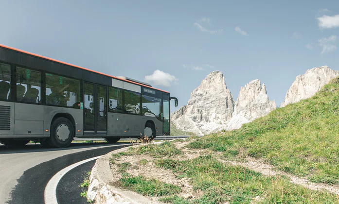 A bus drives along a road in the Dolomites.