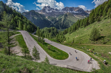 I ciclisti su strada percorrono le serpentine nella discesa del Passo di Campolongo.