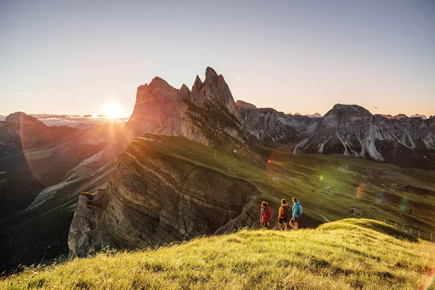 View of the Seceda mountain in summer, three people are walking in the foreground