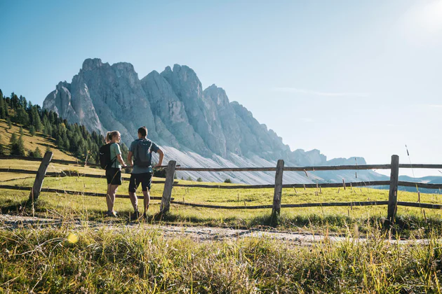 Due escursionisti guardano le montagne nella Val di Funes