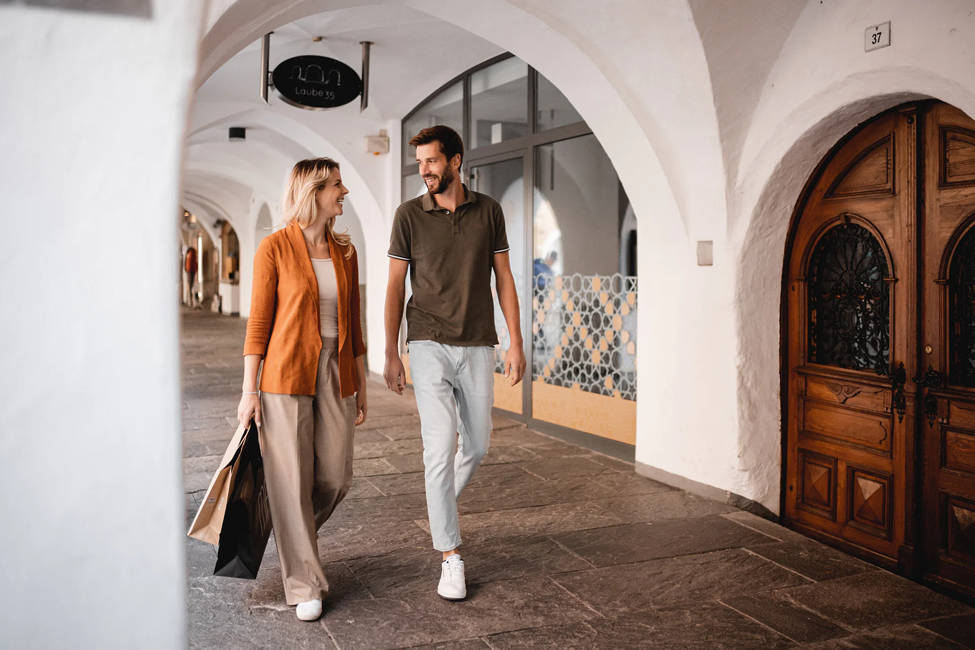 Un uomo e una donna passeggiano sotto i portici del centro storico