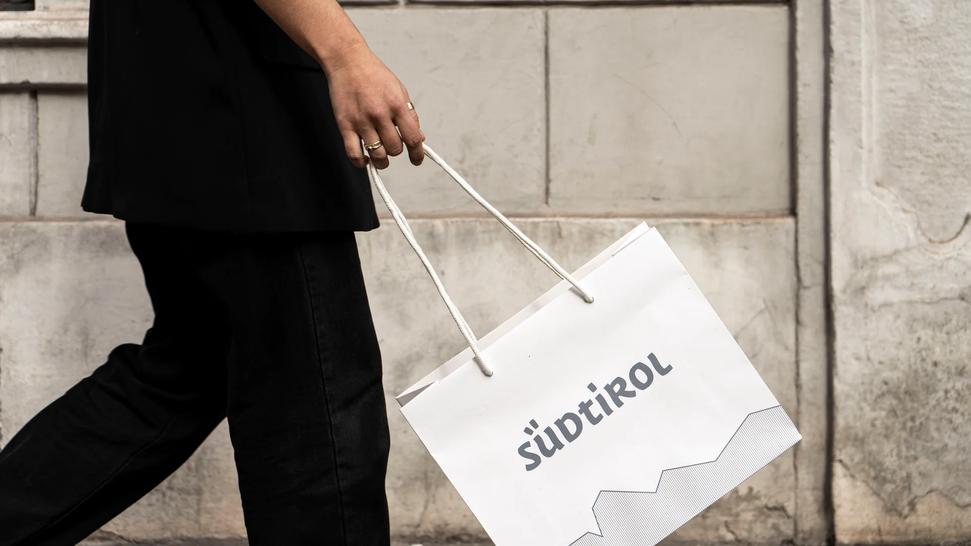 Una persona cammina tenendo in mano una shopper con stampato il marchio ombrello Alto Adige