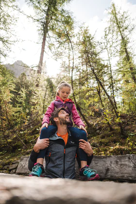 Un papà porta sua figlia sulle spalle nel bosco