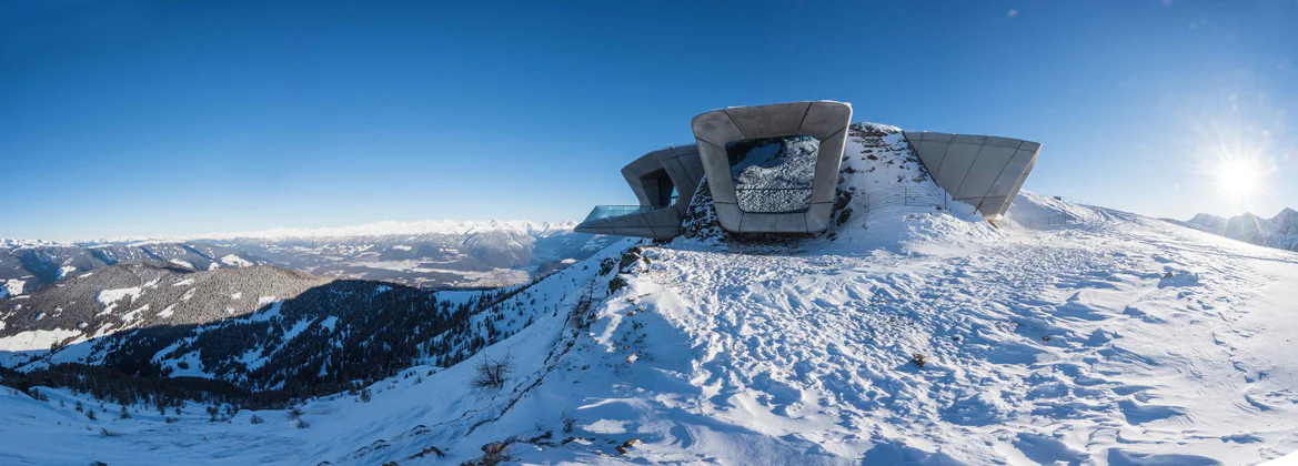 Vista invernale del Messner Mountain Museum Corones al Plan de Corones con il sole splendente sull'orizzonte