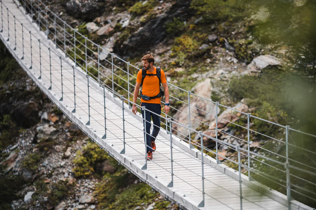 Una persona attraversa un ponte in montagna