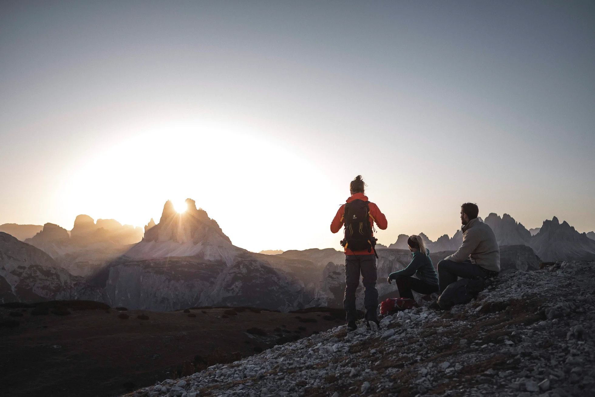 Due escursionisti ammirano il sorgere del sole dalla vetta di una montagna