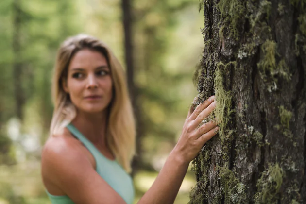 Femme en train de prendre un bain de forêt, dans un coin de nature verdoyant.