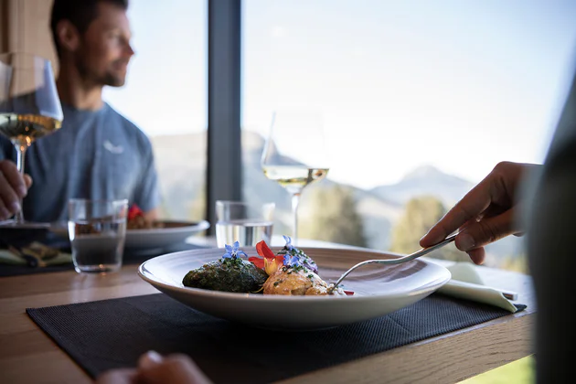 Due persone siedono ad un tavolo con vista in un ristorante mentre assaporano un piatto della cucina locale