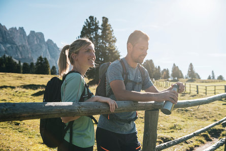 Two people walking with a mountain in the background