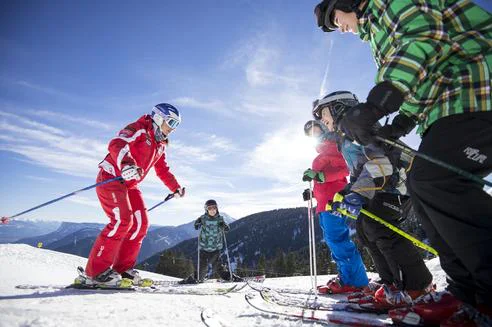 Plusieurs enfants en train de prendre des cours à l'école de ski