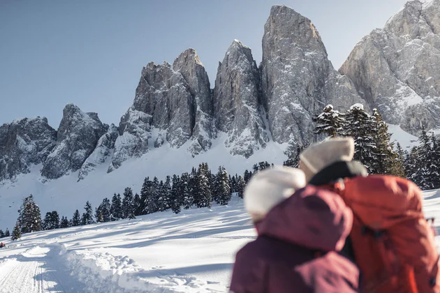 Due persone fanno una passeggiata invernale sulla neve tra le montagne 