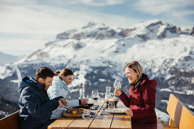 3 people eating on the terrace of a ski hut