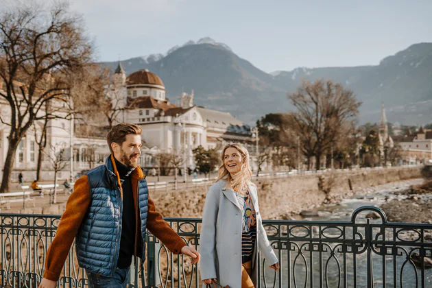 Un uomo e una donna passeggiano lungo il fiume a Merano