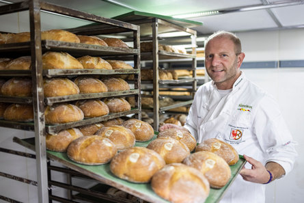 Meester-bakker Hannes Schwienbacher haalt een plaat vol broden van bakkerij Ultner Brot uit een rek.