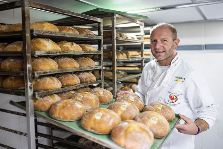 Bäckermeister Hannes Schwienbacher zieht ein Blech voller Ultner Brote aus einem Regal.
