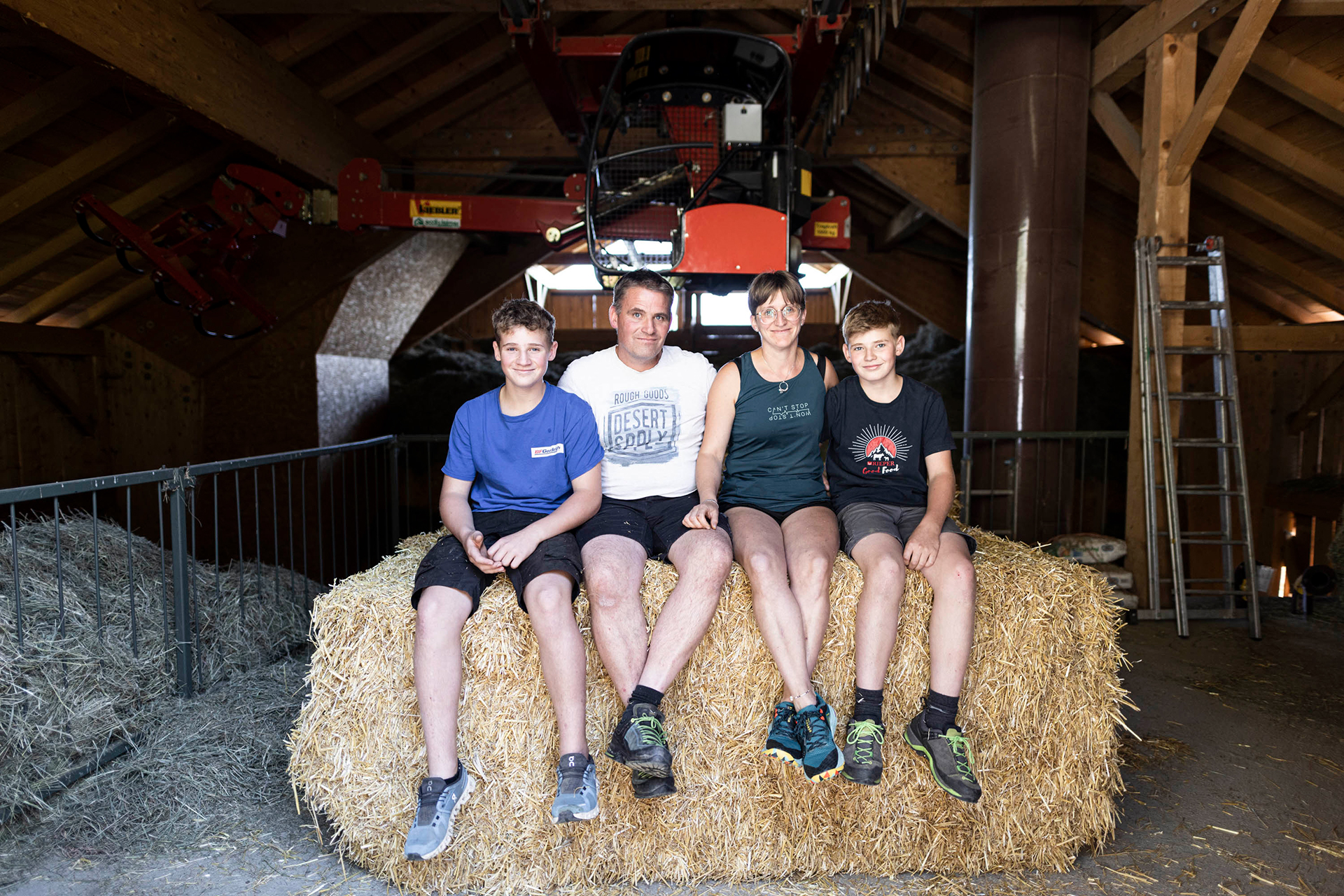 Foto della famiglia Volgger seduta su una balla di fieno nel fienile