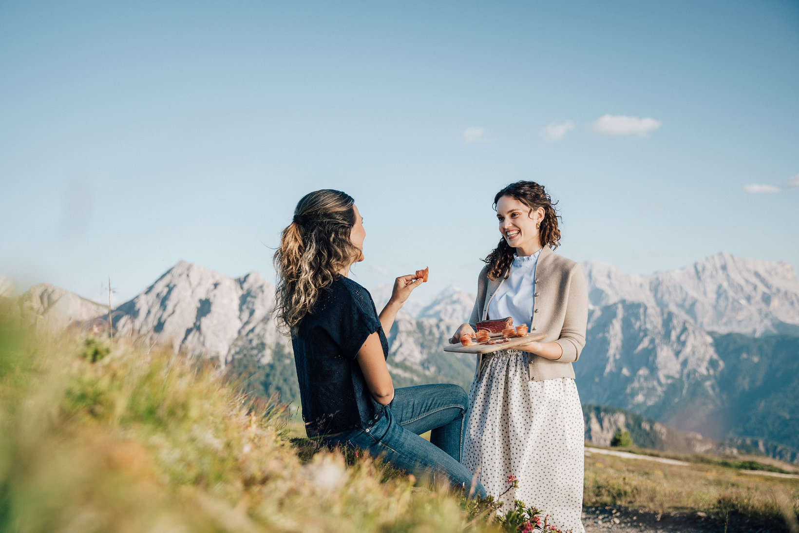 Deux femmes dégustent du speck du Sud-Tyrol devant un paysage de montagnes