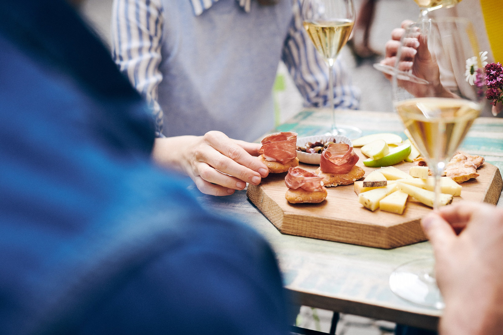 Vrienden zitten bij elkaar en genieten op een zonnige dag van een aperitief met spek en kaas in Bolzano/Bozen