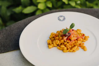 Eine Portion knuspriger Spätzle mit geröstetem Speck und Kräutern serviert.