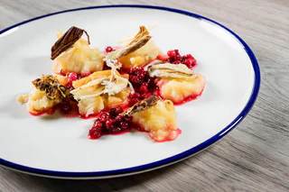 Zart gebackene Bratäpfel, serviert mit leuchtend roten Preiselbeeren und knusprigen Apfelchips.