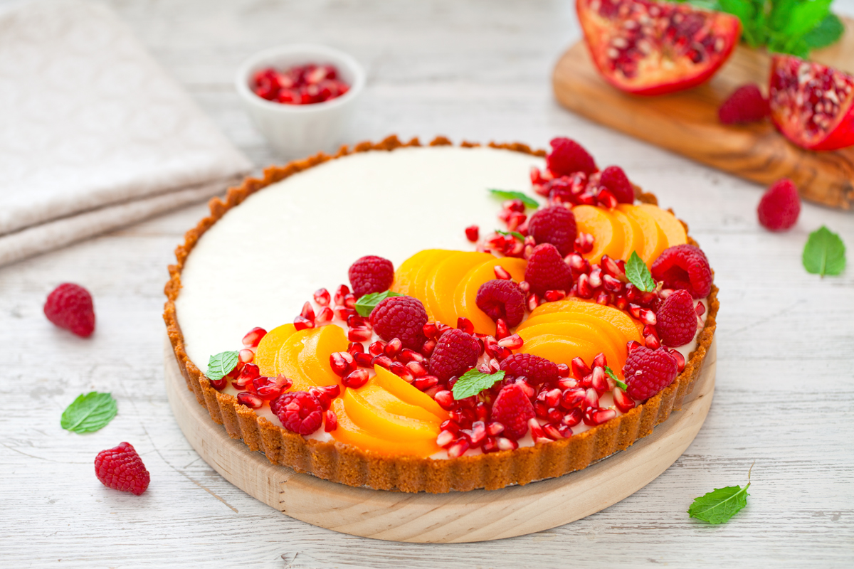 Eine Joghurt-Panna-Cotta-Torte garniert mit Pfirsichen und roten Früchten