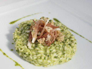 Creamy green risotto topped with fine strips of ham, cheese, and crunchy crumbs.