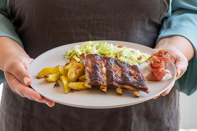 Costine con marinata di miele, patate al forno e insalata di cappuccio con speck dell’Alto Adige