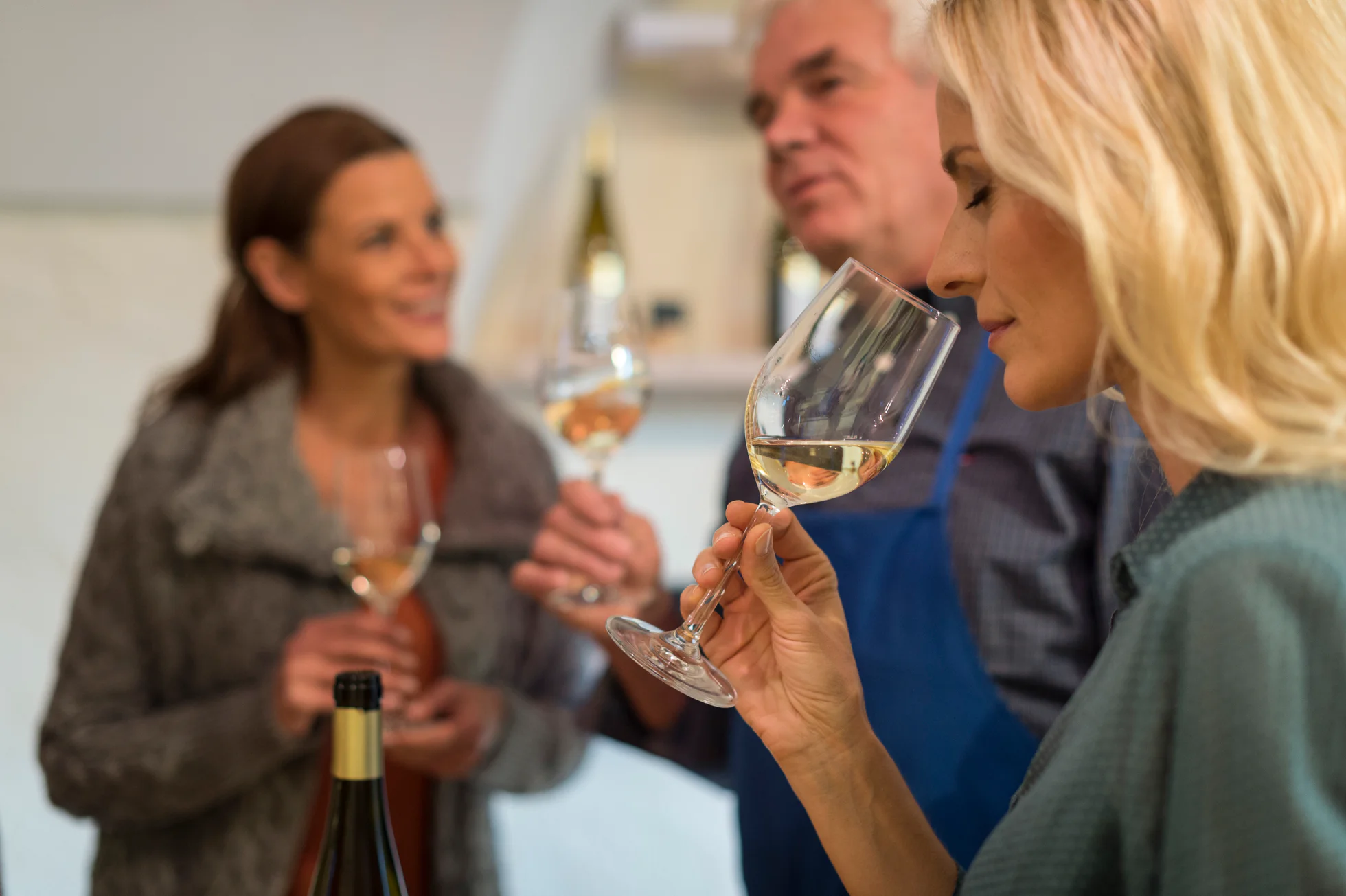 Due donne e un uomo si gustano del vino bianco della Valle Isarco