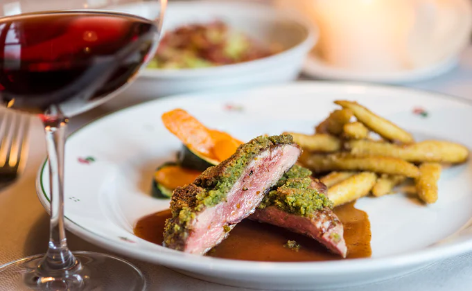 Ein Teller Steak und Pommes, im Vordergrund ein Glas Rotwein