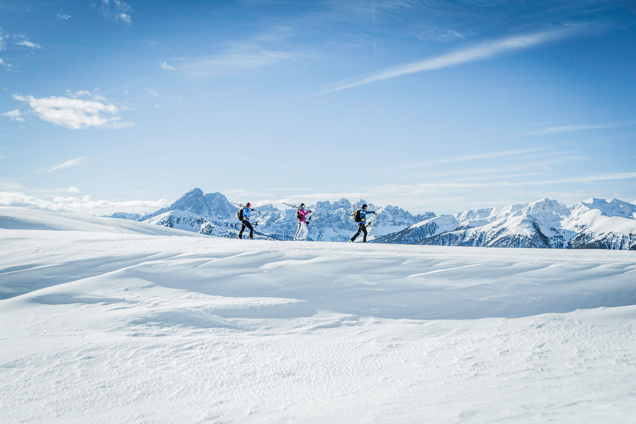 Tre persone con gli sci da alpinismo camminano in un paesaggio invernale