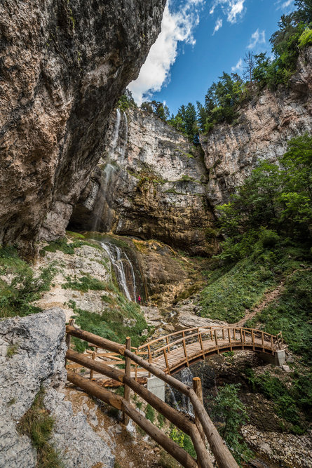 Persone percorrono un canyon attraverso una serie di ponti. Sul lato sinistro si intravede una cascata e e tutt'intorno si è circondati da imposanti rocce e vegetazione.