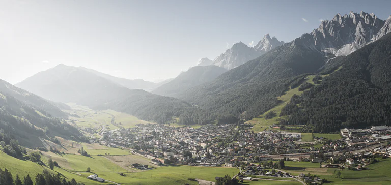 Vista su San Candido con un'ampia vallata verde e maestose montagne sullo sfondo