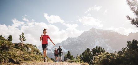 Una famiglia di tre persone cammina nel Parco Naturale dell Stelvio con l'Ortles sullo sfondo