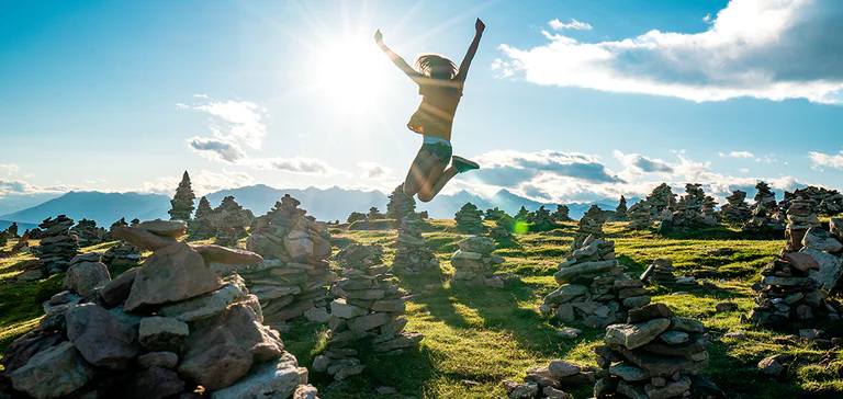 Una persona fotografata mentre salta su un altipiano cosparso di omini di pietra
