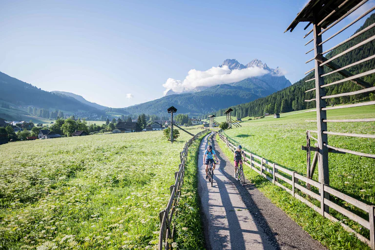 Due ciclisti si godono un percorso immerso in un paesaggio verdeggiante in una giornata di sole a Sesto