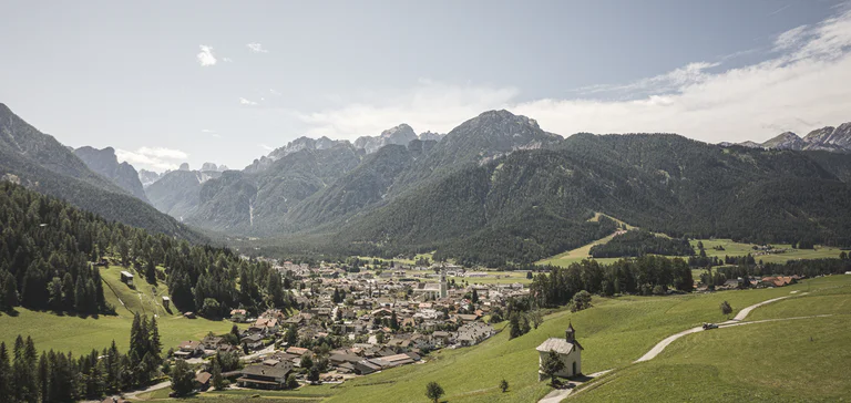 Vista panoramica sul paese di Dobbiaco e pendii boschivi sullo sfondo