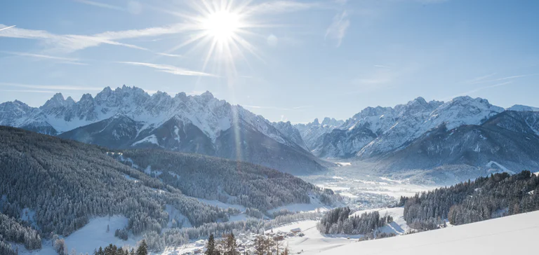 Vista panoramica sul paese di Dobbiaco e pendii boschivi sullo sfondo