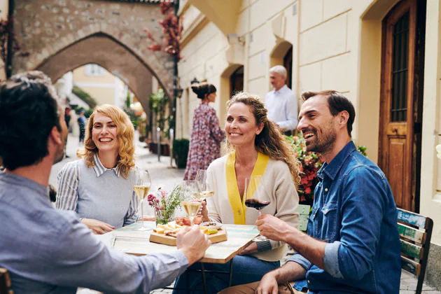 Groupe de personne en train de boire l'apéritif à une table dans une ville du Sud-Tyrol