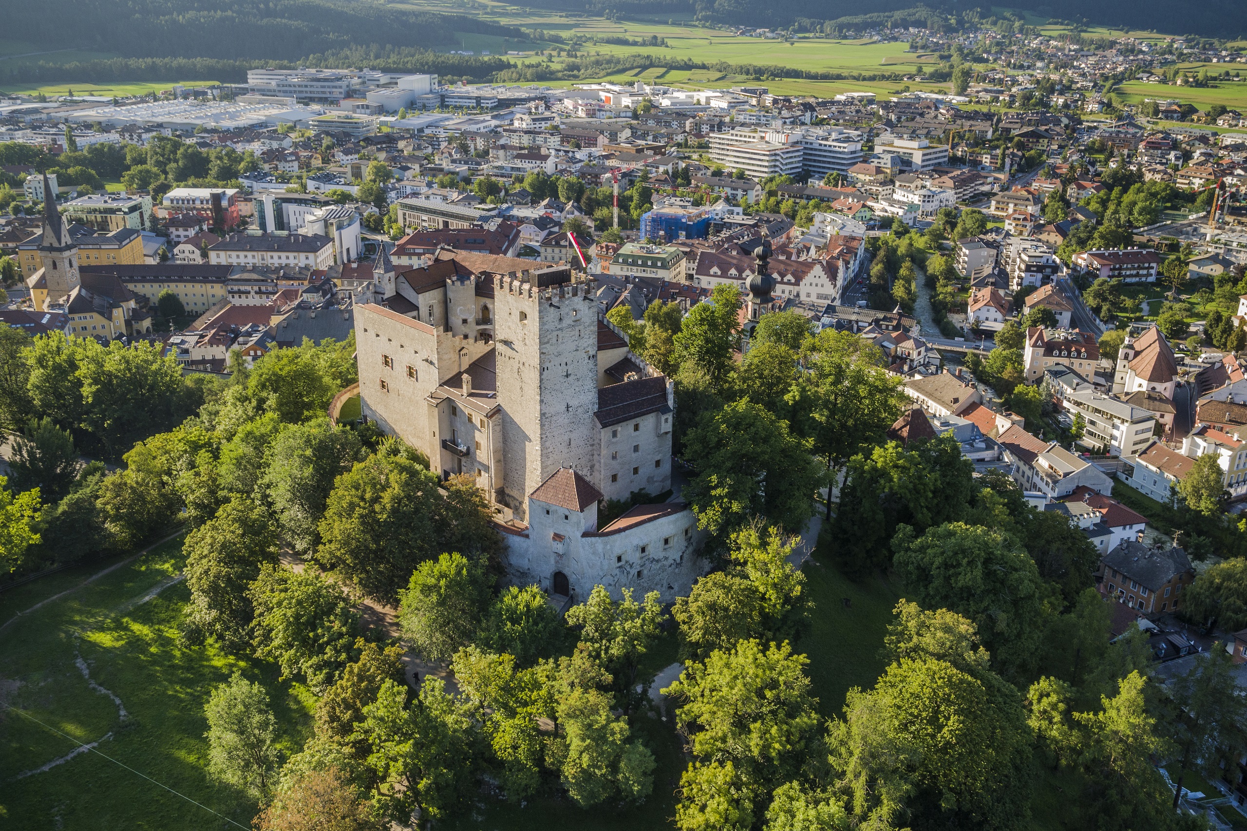 Vista del Castello di Brunico circondato da alberi e il centro abitato sullo sfondo