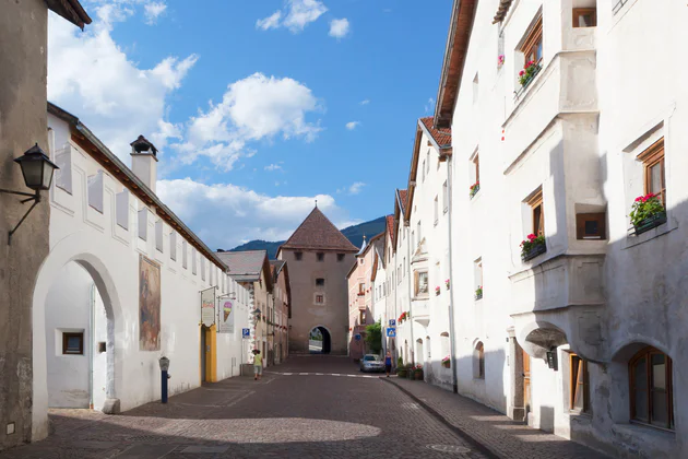 Vista sulla via principale del centro storico della città di Glorenza, ai lati le facciate merlate in fondo una torre