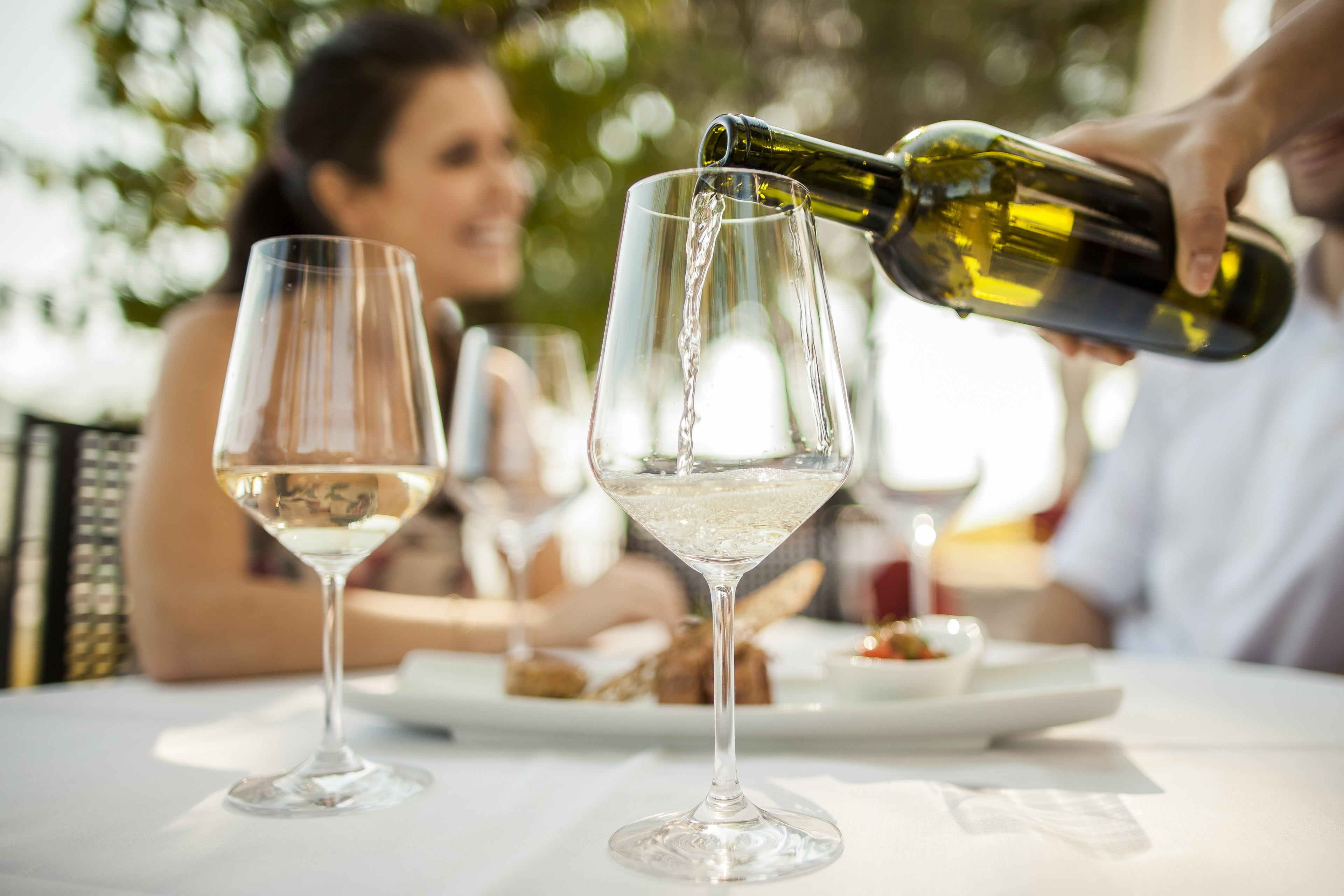 Vino bianco dell'Alto Adige viene versato in calici di vetro con due persone sullo sfondo