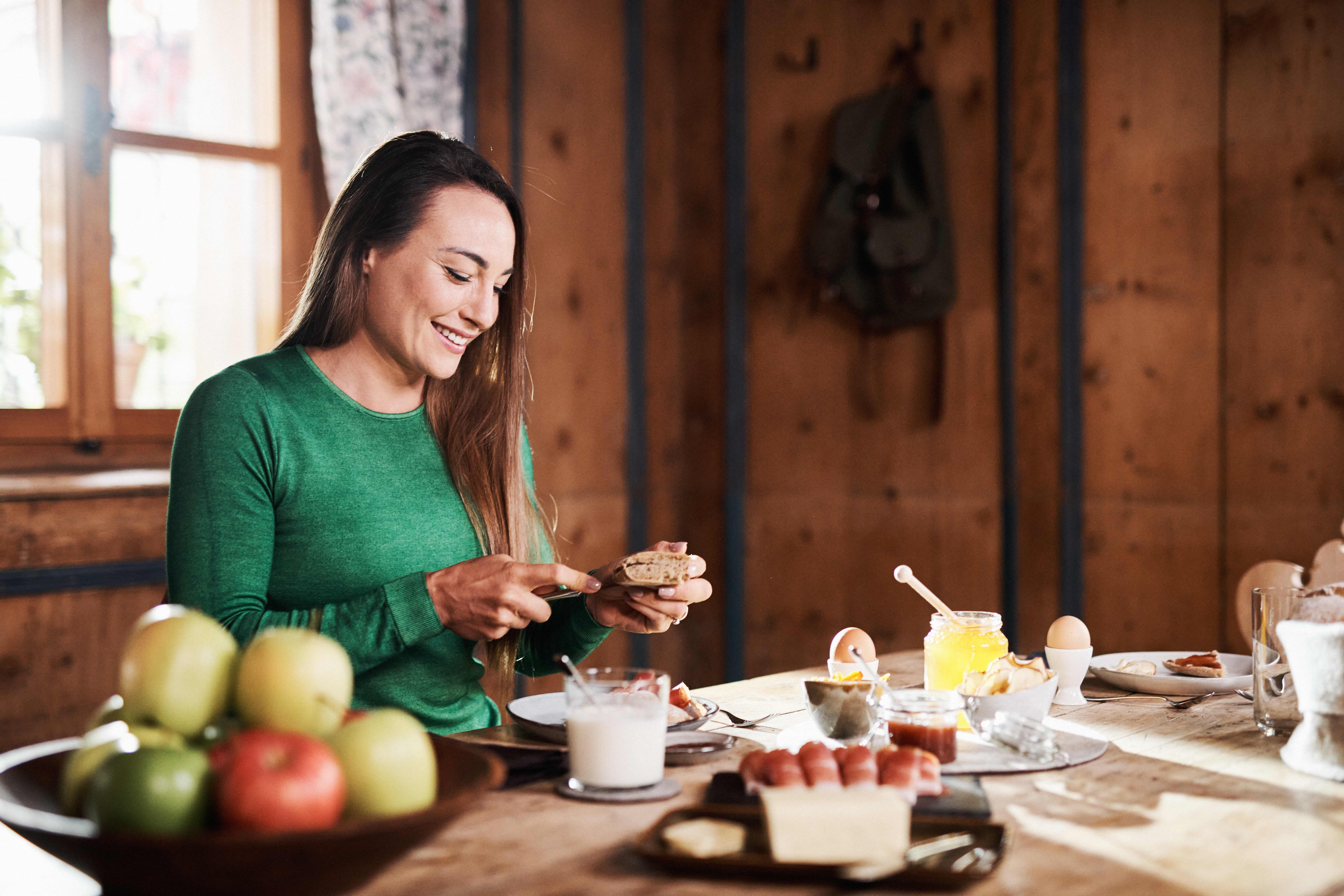 Biatlete Dorothea Wierer zit aan de ontbijttafel en snijdt een broodje.