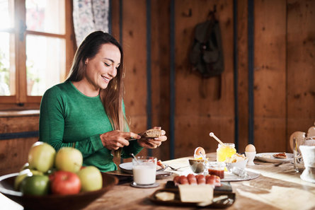 Biathlonistka Dorothea Wierer siedzi przy śniadaniu i kroi bułkę