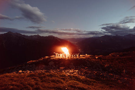 Im Passeiertal mit Blick in Richtung Meran haben sich Einheimische an einem Juni-Abend um ein traditionelles Herz-Jesu-Feuer versammelt.
