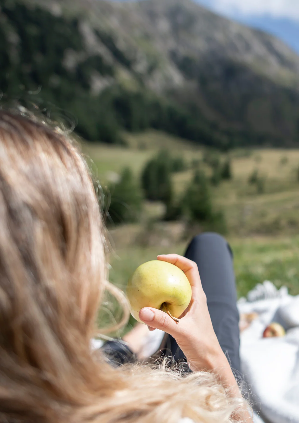 Eine Person isst einen Apfel, während sie auf einer Wiese liegt